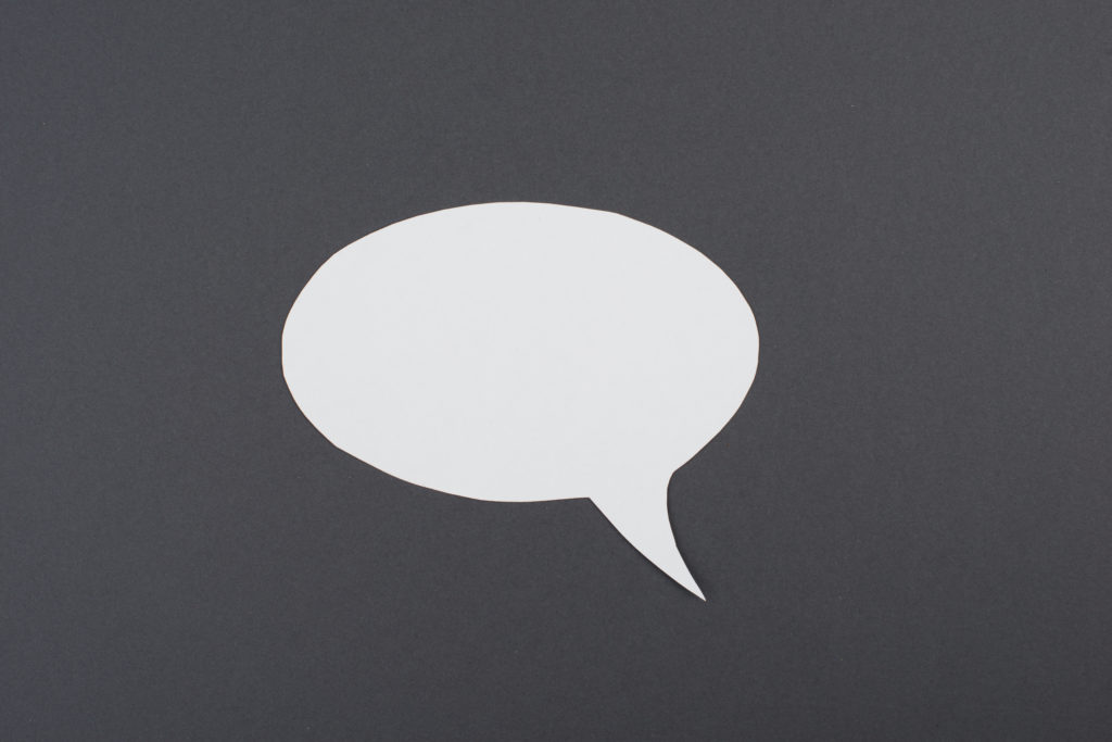 Empty speech bubble, white paper on a dark grey background, copy space for text